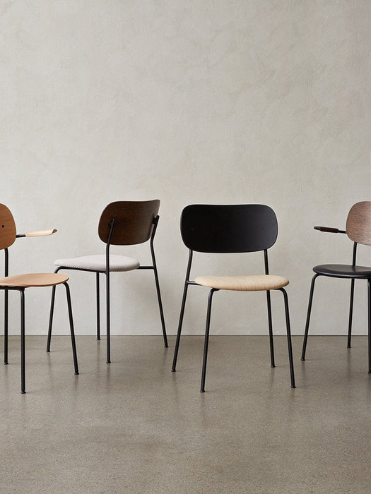 A row of four Co Dining Chairs with black steel frames, showcasing various oak veneer and upholstered finishes.