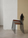 A side view of five Co Dining Chairs stacked in various upholstery and wood veneer finishes against a two-tone wall.