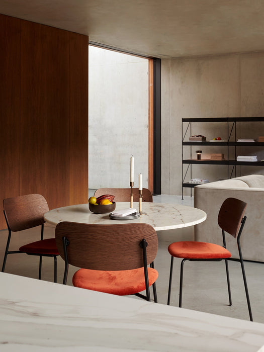 Four Co Dining Chairs with orange seats around a marble Column Table in a dining room with concrete walls and a Zet shelf.