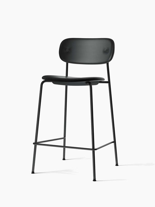 The Co Counter Chair, fully upholstered in black Dakar leather with a slender black steel frame, viewed from an angle.