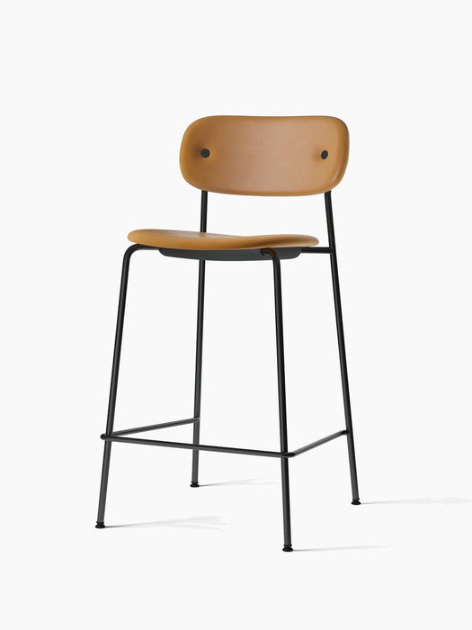 Angled view of the Co Counter Chair, fully upholstered in tan Dakar leather with a slender black steel frame.