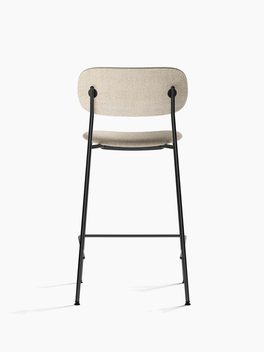 Back view of the Co Counter Chair, Fully Upholstered, showing its light beige fabric seat and backrest and black metal frame.