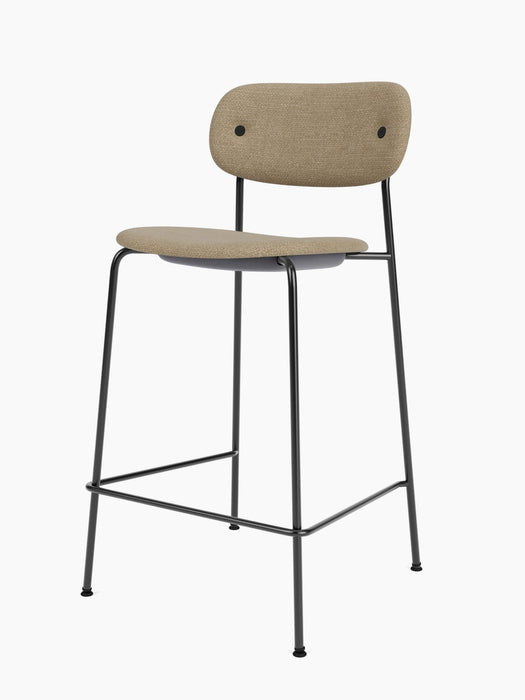 The Co Counter Chair, Fully Upholstered, shown at an angle, featuring light brown fabric and a slender black metal frame.