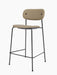 The Co Counter Chair, Fully Upholstered, shown at an angle, featuring light brown fabric and a slender black metal frame.