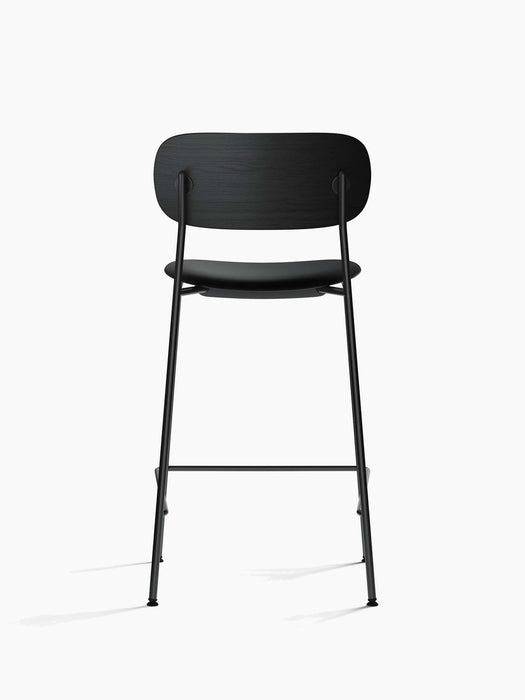 Back view of the Co Counter Chair with an upholstered seat, showing the black oak backrest and slender black steel frame.