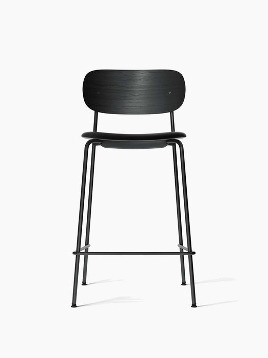 The Co Counter Chair in black oak with a black leather upholstered seat and a black steel frame, viewed from the front.