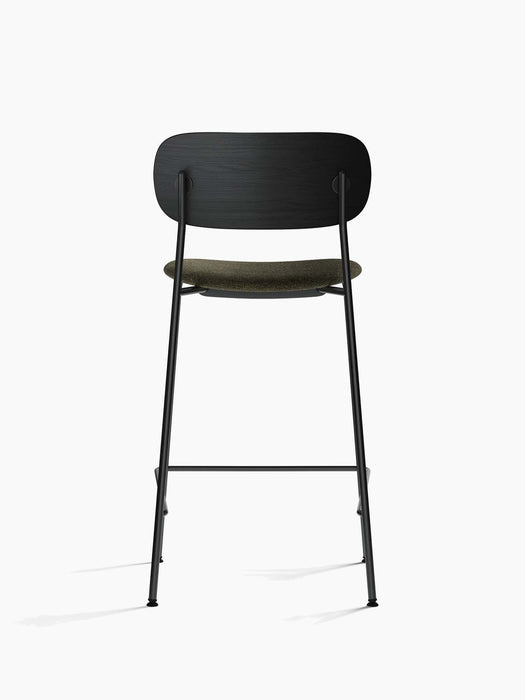 Rear view of the Co Counter Chair with a black oak backrest, moss-coloured upholstered seat, and a slender black steel frame.