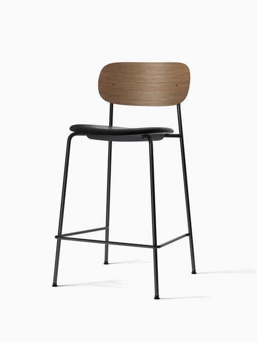 Co Counter Chair, Seat Upholstered, with a dark oak back, black leather seat, and black steel frame, viewed at an angle.