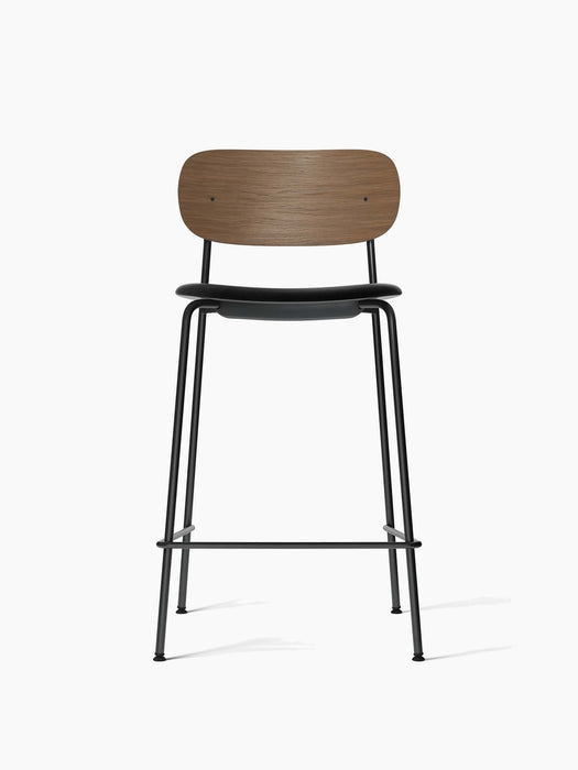 Co Counter Chair from the front, with a dark stained oak backrest, black leather seat, and thin black steel frame.