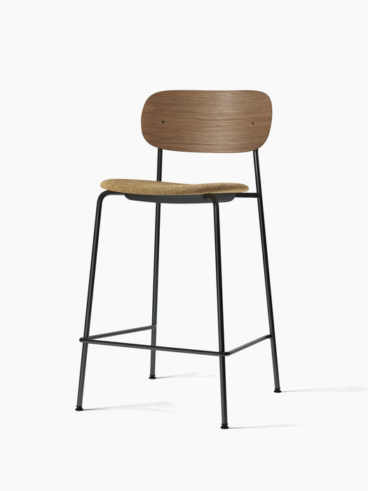 Co Counter Chair, with a dark stained oak back, a textured beige bouclé upholstered seat, and a black steel frame.