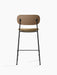 The Co Counter Chair, shown from the back, features a dark stained oak backrest, brown bouclé seat, and black steel frame.