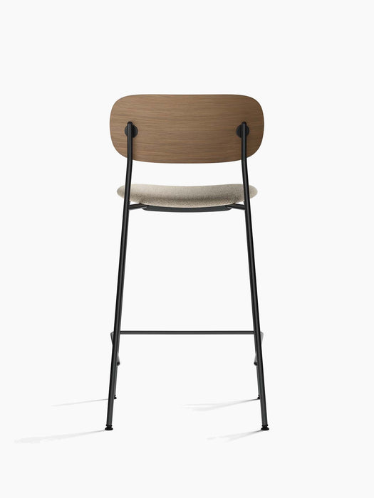 Back view of the Co Counter Chair, Seat Upholstered, with dark stained oak backrest, upholstered seat, and black frame.
