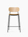 Front view of the Co Counter Chair with a natural oak backrest, tan upholstered seat, and a slender black steel frame.