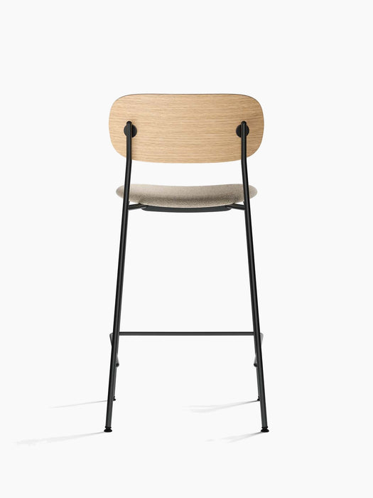 Back view of the Co Counter Chair with a natural oak backrest, upholstered seat, and slender black steel frame.