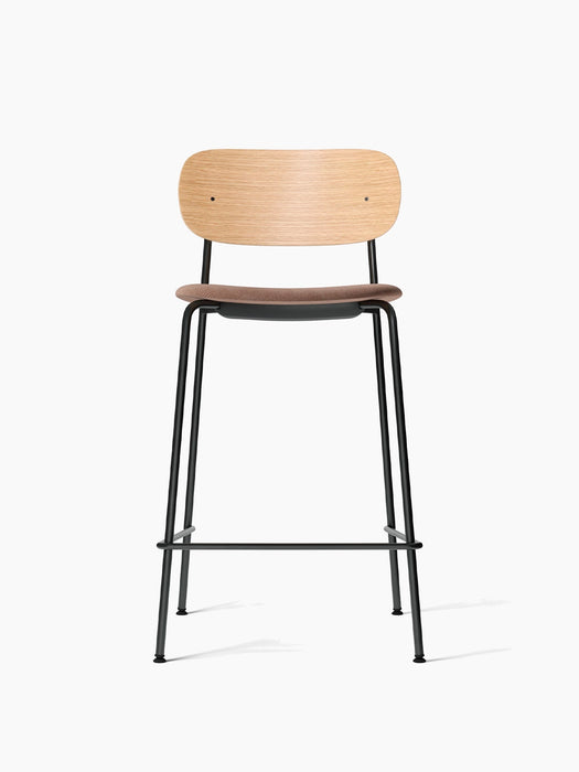 Front view of the Co Counter Chair, natural oak backrest, light brown upholstered seat, and a slender black steel frame.