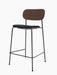 Angle view of the Co Counter Chair, Seat Upholstered, with a dark stained oak backrest, black seat, and slender black frame.