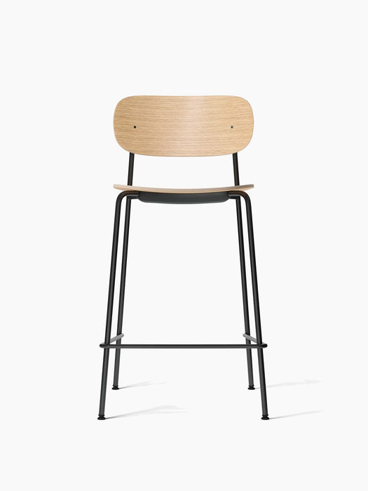 Front view of the Co Counter Chair in natural oak veneer with a black seat and a slender, black powder-coated steel frame.