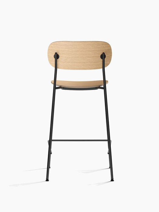 Back view of the Co Counter Chair, Veneer, showing its natural oak backrest and seat on a slender, powder-coated black frame.