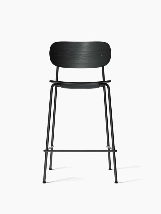 Frontal shot of the Co Counter Chair with a black oak veneer seat and backrest on a slender, black powder-coated steel frame.