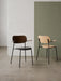 A side-by-side shot of two Co Dining Chairs with armrests: one dark stained oak with a black seat, the other natural oak.