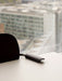 Detailed view of the black Co Dining Chair's armrest on a white table, with a blurred cityscape through a window.