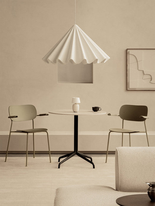 Two olive Co Dining Chairs with armrests placed at a round Harbour Column Dining Table under a white Dancing Pendant light.