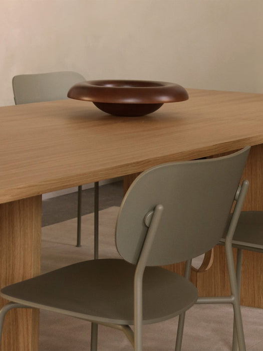 Close-up of an olive Co Dining Chair, Outdoor placed by a light oak Androgyne Dining Table with a Rond Bowl.