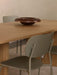 Close-up of an olive Co Dining Chair, Outdoor placed by a light oak Androgyne Dining Table with a Rond Bowl.