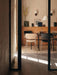 A modern dining room with Co Dining Chairs in cream bouclé and black upholstery with chrome frames around a dark table.