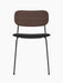 A front view of the Co Dining Chair with a dark stained oak backrest, a black upholstered seat, and a slender black frame
