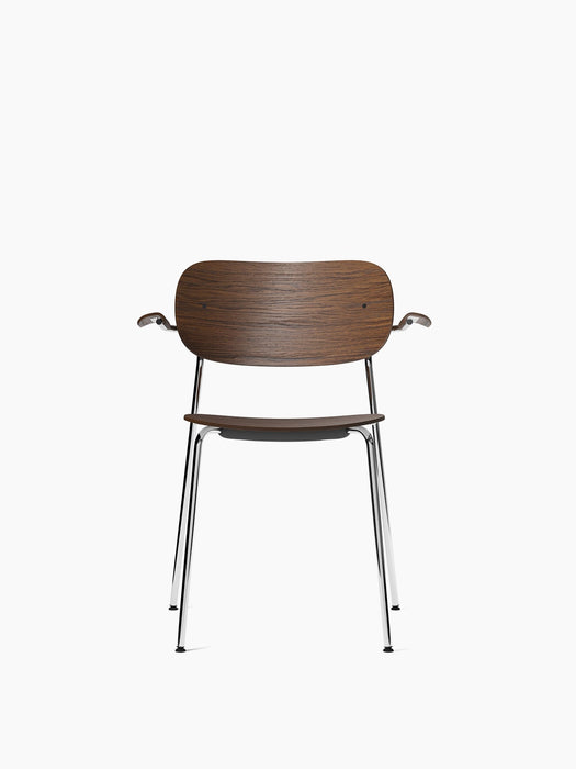 Front view of the Co Dining Chair with armrests, featuring a dark stained oak seat and back on a slender chrome frame.
