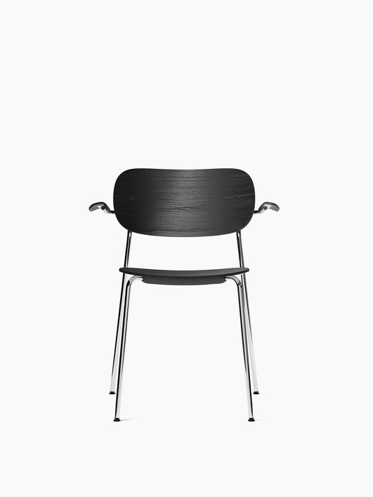 Front view of the Co Dining Chair with Armrest, featuring a black oak veneer seat and backrest set on a slender chrome frame.