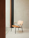 The Co Lounge Chair, with a natural oak backrest, tan leather seat, and black frame, sits on a thick, cream-coloured rug.