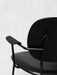 A black and white close-up of the Co Lounge Chair, highlighting the black wood armrest, round back, and slender metal frame.