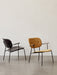 A black Co Lounge Chair and a yellow fabric Co Lounge Chair are shown side by side in a minimalist room with a grey floor.