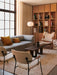 Two Co Lounge Chairs with bouclé upholstery in a modern living room setting with a sofa, bookshelf, and large window.