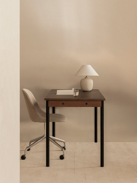 The Co Table styled as a desk with a Harbour Side Chair and Torso Table Lamp. The setting is minimalist against a beige wall.