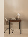 The Co Table styled as a desk with a Harbour Side Chair and Torso Table Lamp. The setting is minimalist against a beige wall.