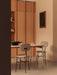 The Co Table is set with two Afteroom Dining Chairs in a minimalist room with oak wall cabinets and a black Releve Platter.