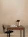 A Co Task Chair is neatly placed at a dark wood Co Table, accessorised with a Reverse Table Lamp and a glass of water.