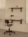 A Co Task Chair at a dark wood Corbel Desk with a Reverse Table Lamp. Above, a Corbel Shelf holds books and a pear.