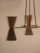 A detailed close-up of the Collector Chandelier, 3, showing a cream hourglass-shaped shade with a polished brass band.