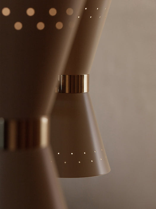 A detailed close-up of the Collector Chandelier, 3, showing its cream metal shades with light perforations and brass details.