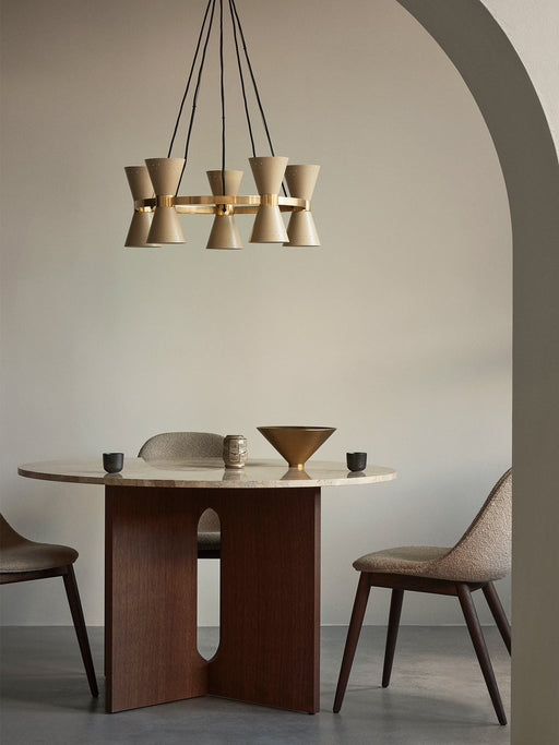 A Collector Chandelier, 5 hanging above a round Androgyne Dining Table set with a Taper Bowl in a room with a beige archway.