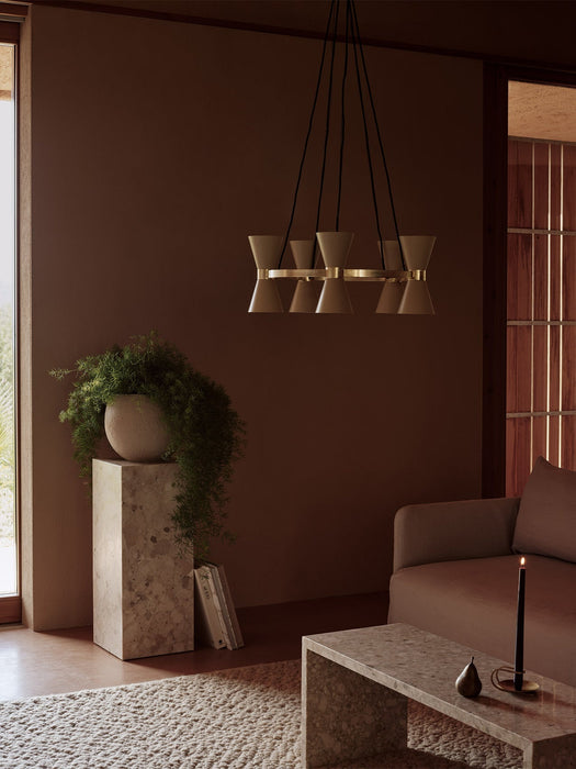 The Collector Chandelier, 5 hangs above a marble Plinth Bridge table in a softly lit, brown-toned living room setting.