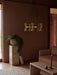 The Collector Chandelier, 5 hangs above a marble Plinth Bridge table in a softly lit, brown-toned living room setting.