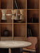 Side view of the Collector Chandelier, 5 hanging above a marble-topped Androgyne Dining Table and a Penguin Dining Chair.