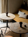 Lounge setting with two marble-topped tables, each displaying a bronze portable Column Table Lamp, next to a yellow sofa.