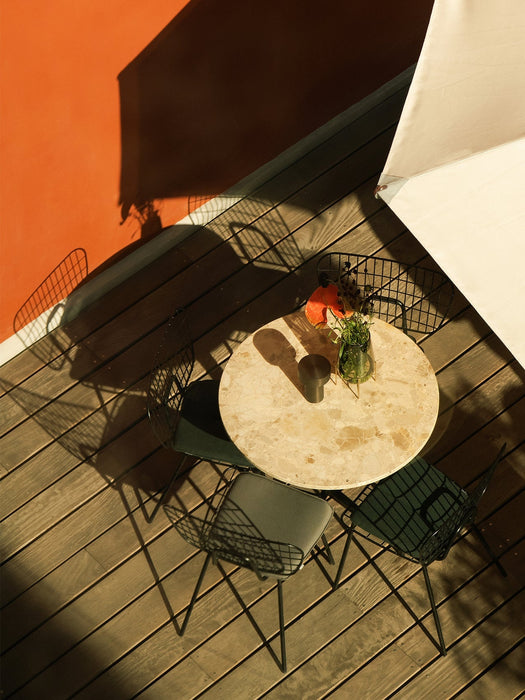 An outdoor setting with a Column Table Lamp on a Harbour Column Table, surrounded by WM String Chairs on a wooden deck.