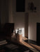 The sculptural, dark grey Converge Book Ends sit on a wooden pedestal, illuminated by a sunbeam in a dimly lit, elegant room.